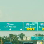 Highway signs with directions to Los Angeles, Long Beach, and Sacramento on a clear day.